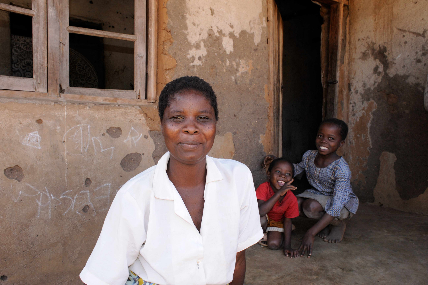 A woman and two children stood smiling outside a house in Mangochi, Malawi